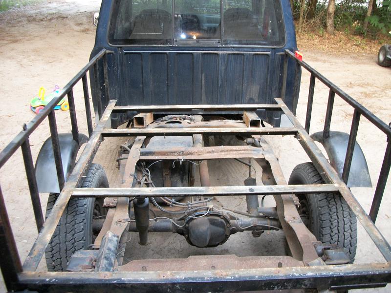 Dark blue truck bed frame with exposed chassis and rear axle