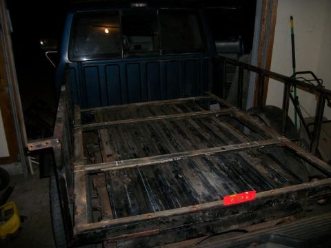 1994 Ford Explorer - Rear view of a blue pickup truck bed a wooden floor and a metal frame structure.