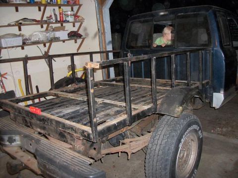 1994 Ford Explorer - A pickup truck with a custom bed rack is shown from the rear, with a child visible in the cab.