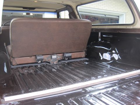 1979 Ford Bronco - The rear cargo area of an SUV shows a folded brown seat and a ribbed floor, with a visible watermark.