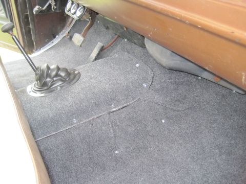 1979 Ford Bronco - The interior of a 1979 Ford Bronco shows its floor-mounted shifter and pedals, covered in grey carpet.