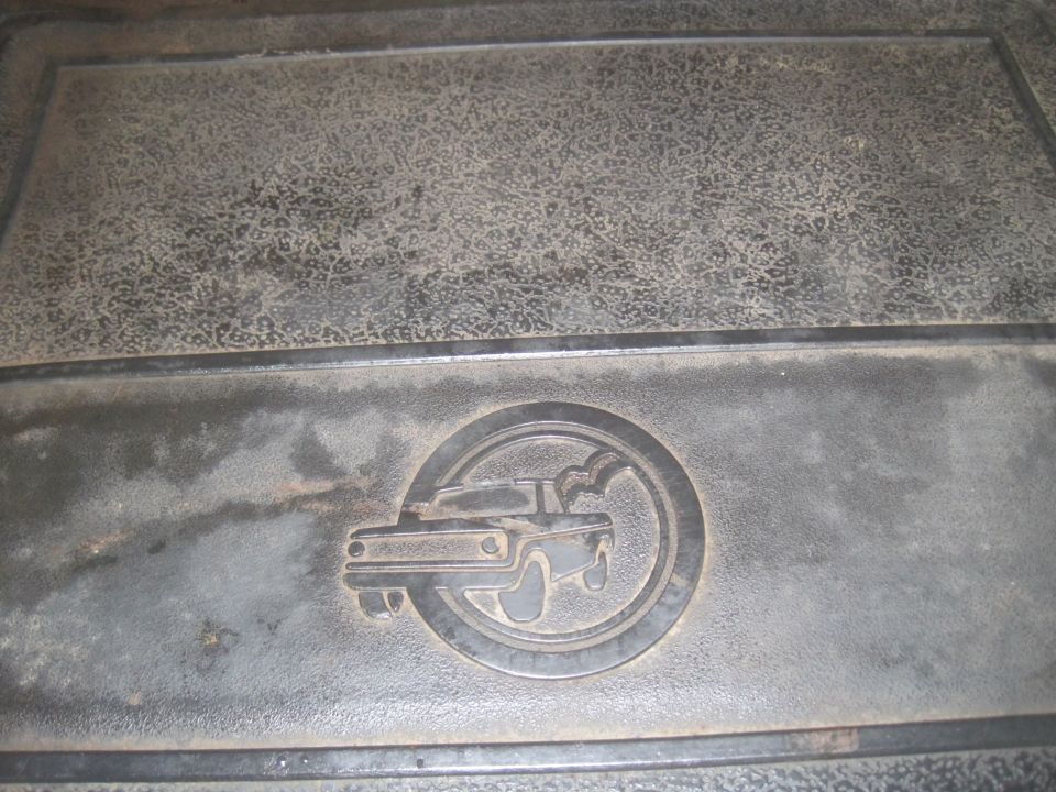 Embossed emblem of a truck inside a circle on a dark floor mat