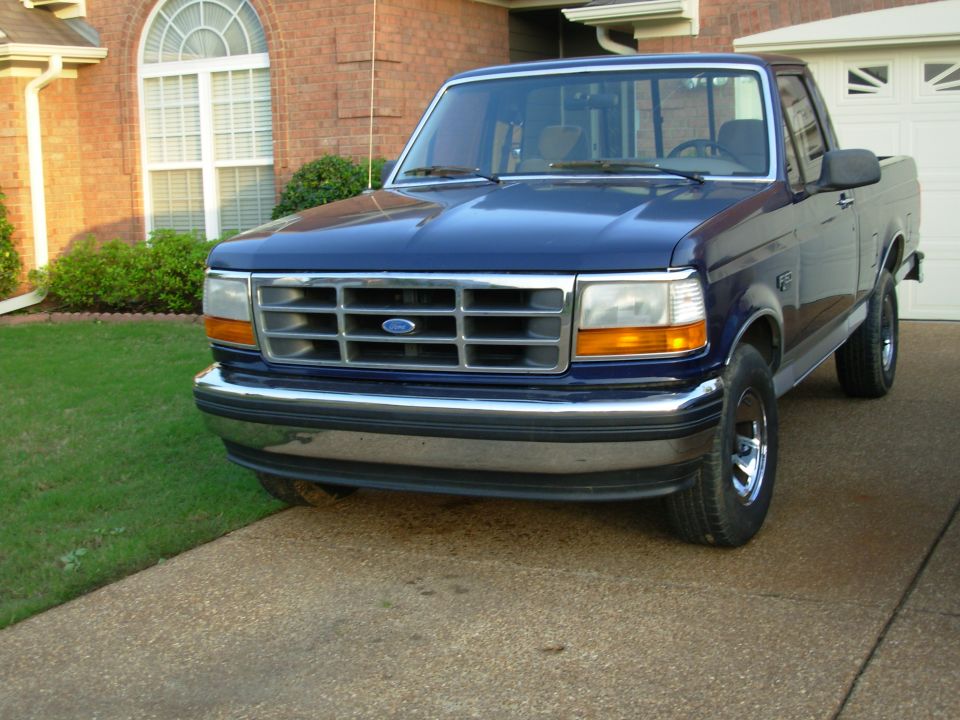 Dark blue Ford F-150 pickup truck parked in a brick-home driveway