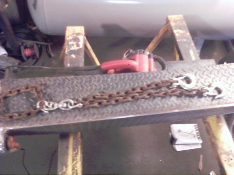 1989 Ford Bronco - A close-up view of heavy-duty chains and a red power tool resting on a textured metal surface.