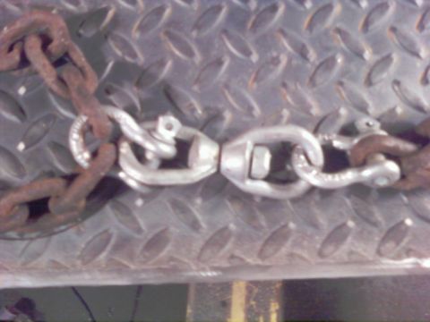 1989 Ford Bronco - Close-up of rusty chain links and a silver swivel connector against a textured metal background.