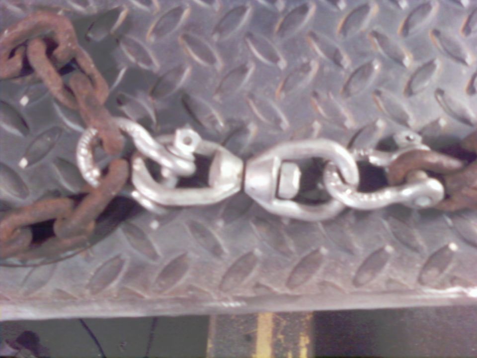 Rusty chain links connected by a silver swivel connector on a diamond plate surface