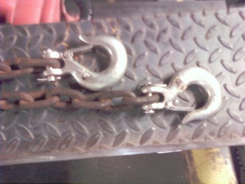 1989 Ford Bronco - Close-up of two tow hooks and a chain, resting on a textured metal surface.