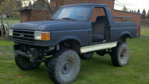 1988 Ford Bronco - This lifted Ford Bronco has a dark blue exterior and is missing its driver's door.