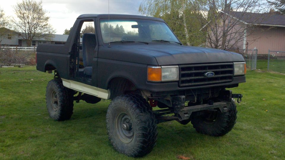 Black lifted 1987 Ford Bronco with doors removed, parked on grass