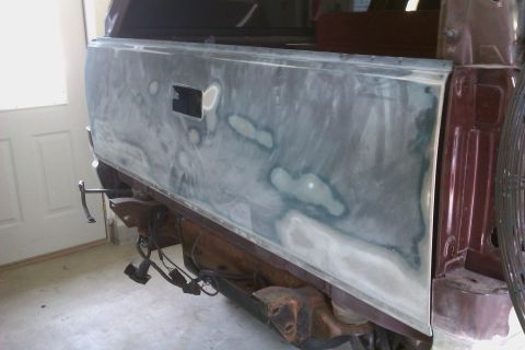 1994 Chevrolet Blazer - The rear of a maroon vehicle is being prepped for paint, with visible body filler and exposed wiring.