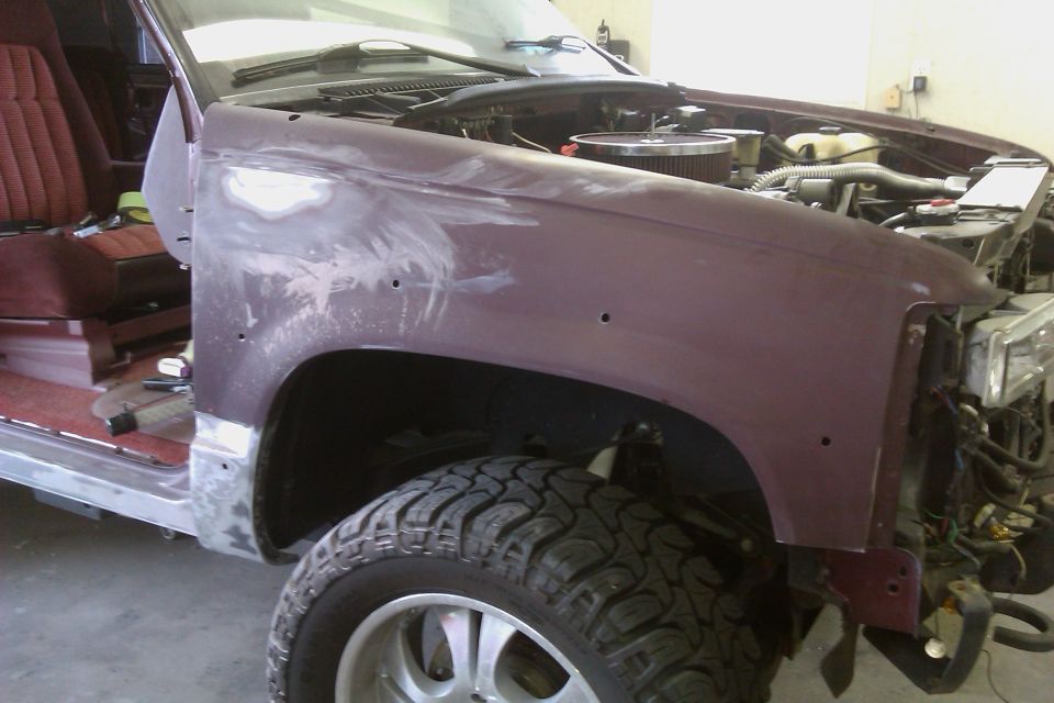 Maroon SUV fender and interior under repair, showing bodywork and engine components