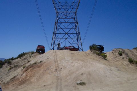 1995 Ford Bronco - Multiple SUVs are parked on a dirt hill beneath a large power line tower on a clear day.