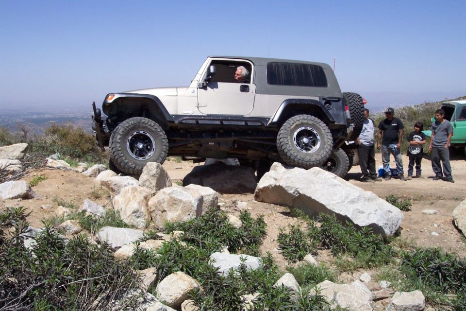 White Jeep Wrangler TJ off-roading over rocks