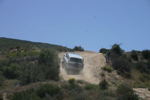 1991 Ford Bronco - A white 1991 Ford Bronco navigates a steep, dusty trail on a sunny day.