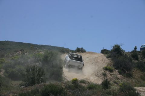 1991 Ford Bronco - A white 1991 Ford Bronco navigates a steep, dusty incline on a sunny day.