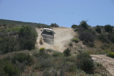 1991 Ford Bronco - White 1991 Ford Bronco navigates a steep, dusty trail off-road.