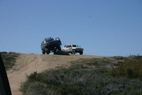 1991 Ford Bronco - Two SUVs navigate a steep dirt incline on a sunny day.