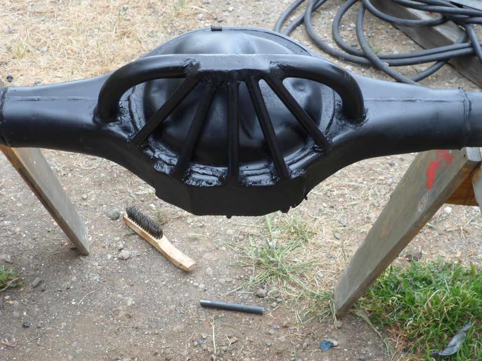 Black painted Ford rear axle differential housing on sawhorses with a brush nearby