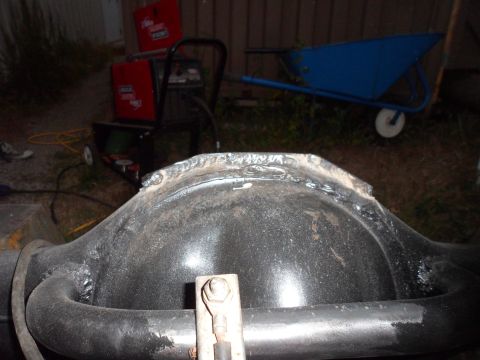1991 Ford Bronco - A differential housing shows significant weld repairs on its upper surface, with a blue wheelbarrow and welding equipment in the background.