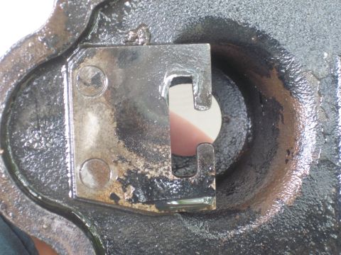 1979 Ford Bronco - A close-up view of a metal component, possibly from a vehicle, a U-shaped bracket and a circular opening.