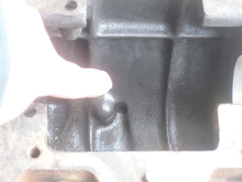 1979 Ford Bronco - Close-up view of an engine block casting, with a finger indicating a specific area.