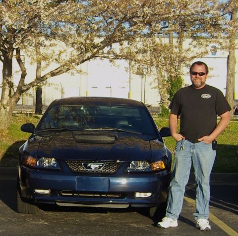 2007 Ford Mustang - Head-on front view of a dark blue New Edge Ford Mustang GT coupe with a hood scoop, mesh pony grille and no front plate, parked on asphalt…