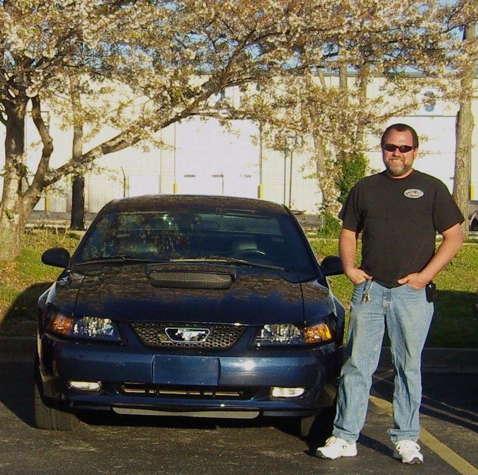 Dark blue New Edge Mustang GT front view with hood scoop, man standing beside it