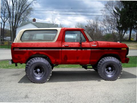 1979 Ford Bronco - This red Ford Bronco, modified with off-road tires, is shown from a side profile against a cloudy sky.