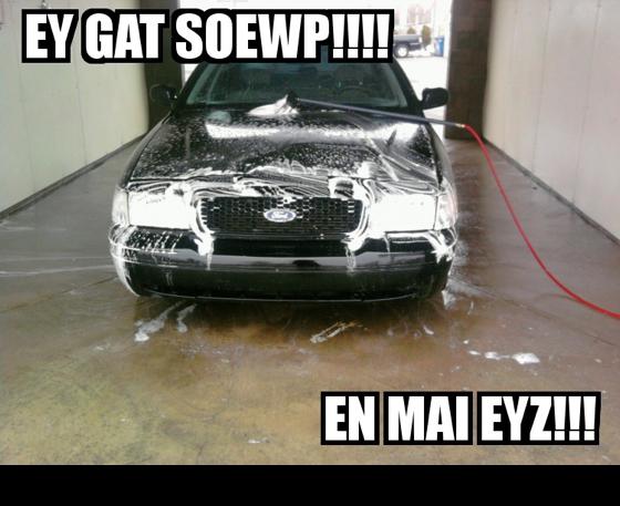 Front view of a black sedan being washed with soap and water. A hose is visible