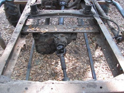 1982 Ford F-100 - Overhead view down a stripped truck frame with the body removed, showing the bare ladder rails and crossmembers, the transfer case with its…