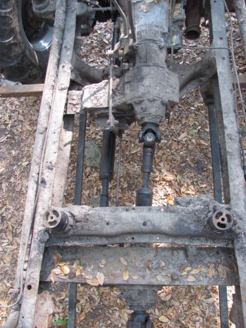 1982 Ford F-100 - Overhead shot down into a bare truck frame with the body removed, showing the transmission and transfer case mounted between the rails with…