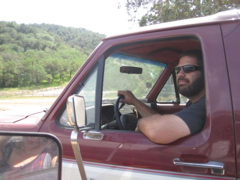 1989 Ford Bronco - Man with beard and sunglasses drives a maroon truck on a sunny day.