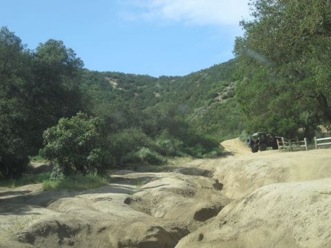 1989 Ford Bronco - A vehicle navigates a dirt trail surrounded by natural landscape.