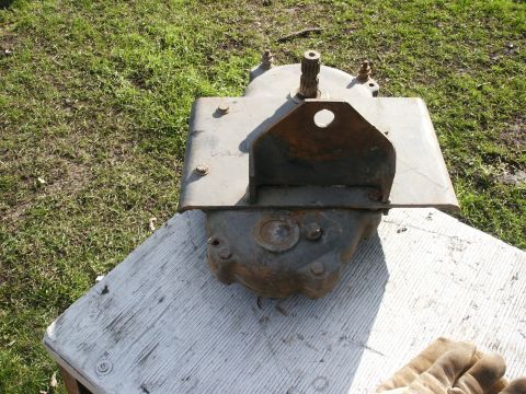 1966 Ford Bronco - A removed cast-iron steering gearbox sitting upright on a weathered white board on the grass, with its splined sector shaft pointing up, a…