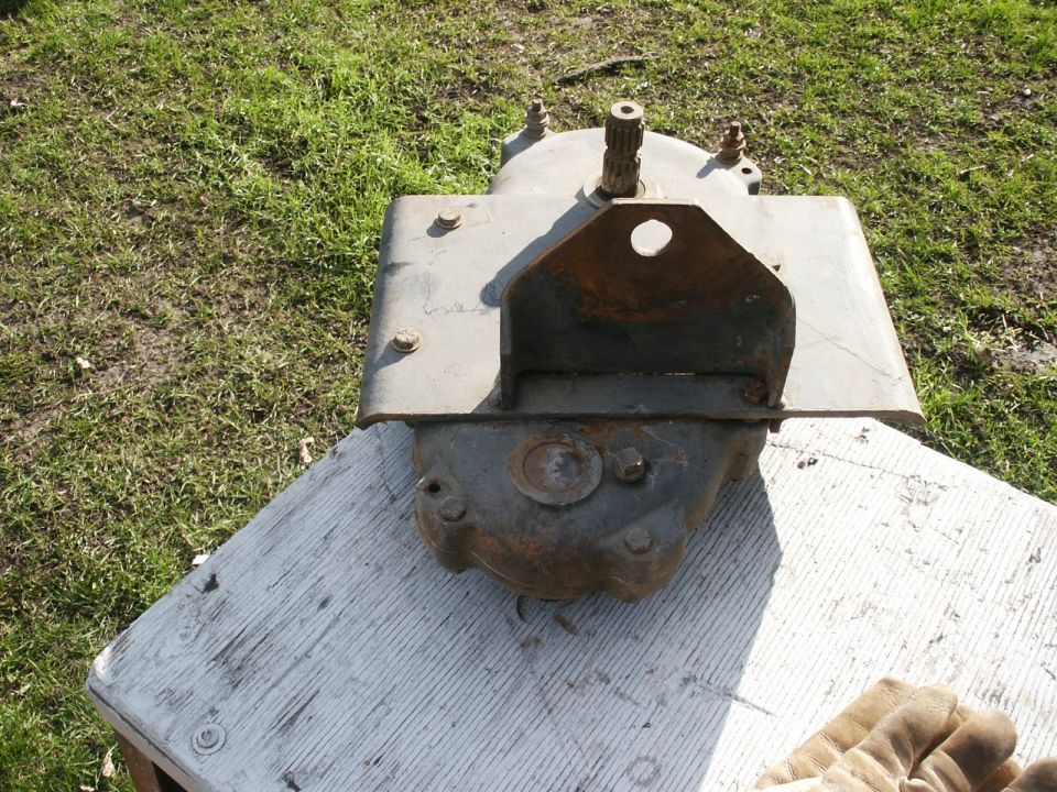 Rusty removed steering gearbox with splined shaft sitting on a board on grass