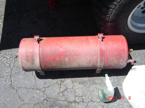 1993 Ford Bronco - A red air tank is shown resting on the ground next to a vehicle's tire.