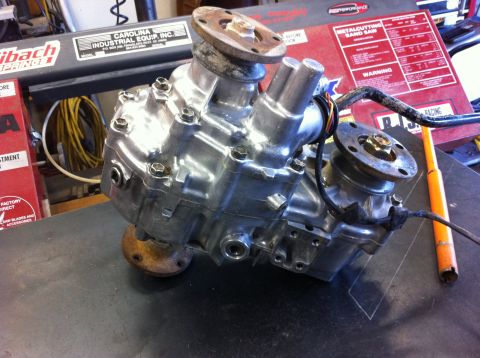 1987 Suzuki Samurai - A polished metal transfer case is shown, likely a part for an off-road vehicle, with visible bolts and flanges.