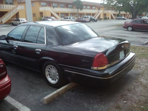 2001 Ford Crown Victoria - Rear view of a black 2001 Ford Crown Victoria parked in a lot with other vehicles.