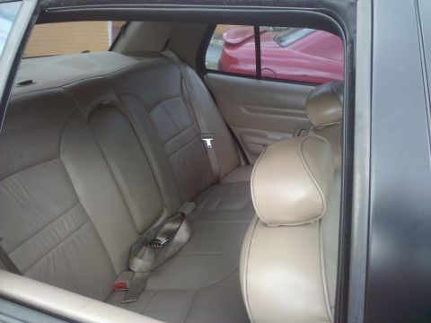 2001 Ford Crown Victoria - Tan leather rear seats are visible inside a 2001 Ford Crown Victoria, with another car seen through the window.