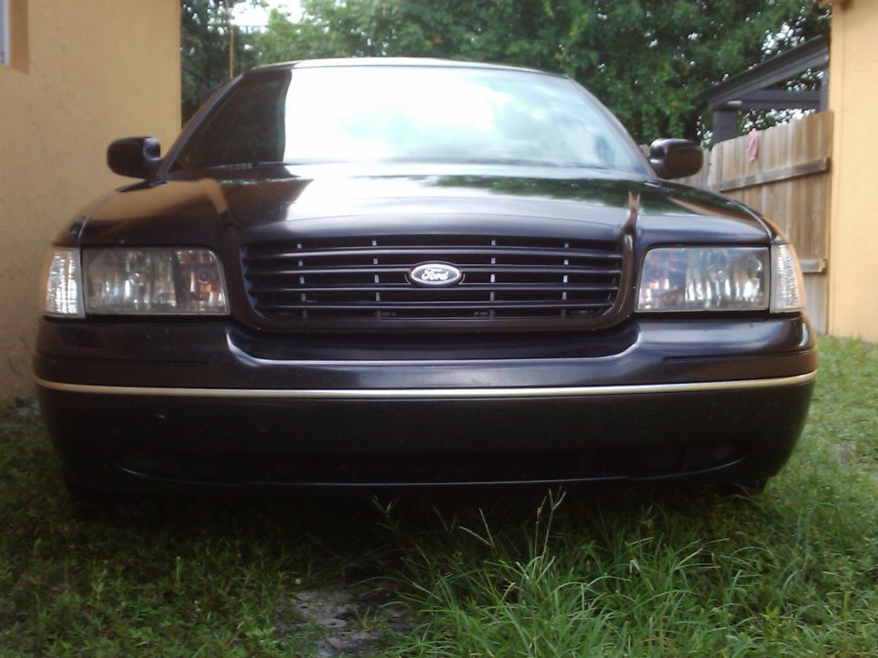 Black 2001 Ford Crown Victoria front view, grille with Ford logo, chrome trim on bumper, parked on grass