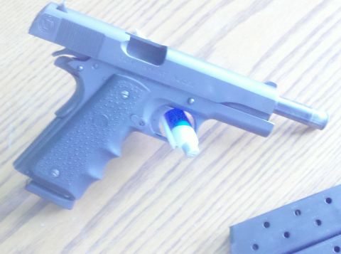 1988 Chevrolet Suburban - A pistol rests on a wooden surface, with a blue and white object inserted into the trigger guard.