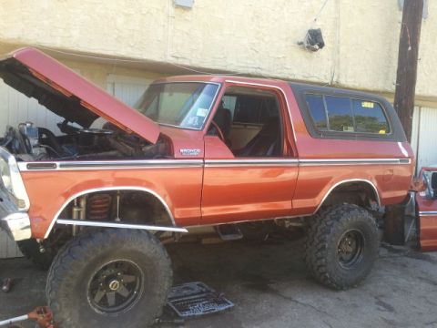 1978 Ford Bronco - This lifted 1978 Ford Bronco is shown with its hood open, revealing the engine bay and suspension modifications.