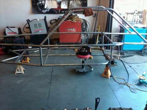 1995 Ford F-150 - A custom-built tube chassis sits on jack stands in a garage, surrounded by welding equipment and tools.