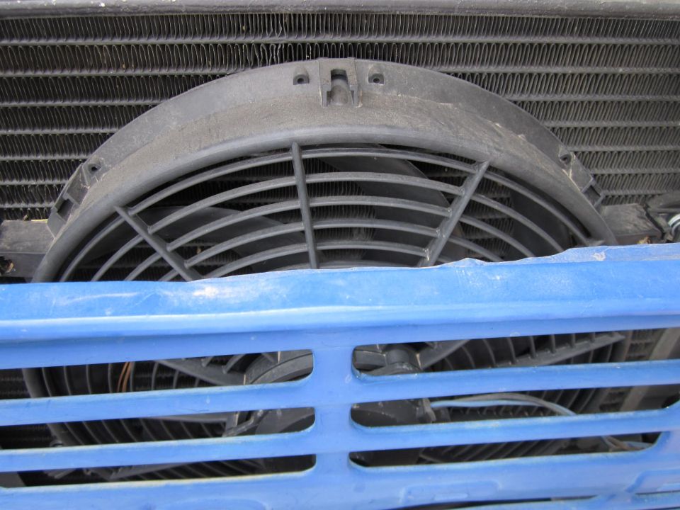 Radiator fan assembly behind a blue grille