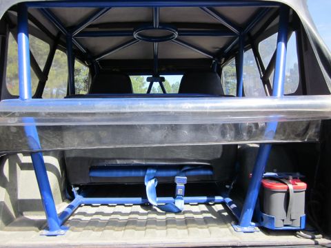 1971 Ford Bronco - The interior of a vehicle is visible, a prominent blue roll cage, seats, and a battery, with a watermark at the bottom.