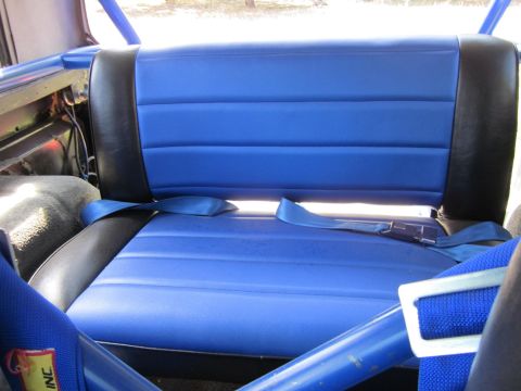 1971 Ford Bronco - Interior view of blue and black seats with seatbelts and roll cage.