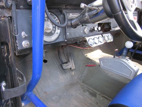 1971 Ford Bronco - The interior of a 1971 Ford Bronco features a blue roll cage, custom gauges, and a floor shifter.