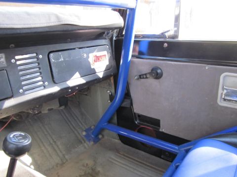 1971 Ford Bronco - The interior of the vehicle features a prominent blue roll cage and a gear shifter. A sticker on the dashboard is partially visible.