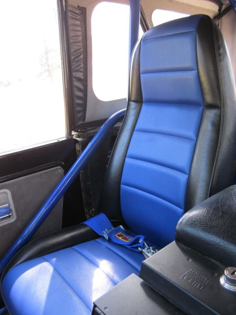 1971 Ford Bronco - The interior features blue and black racing seats, a roll cage, and a racing harness.