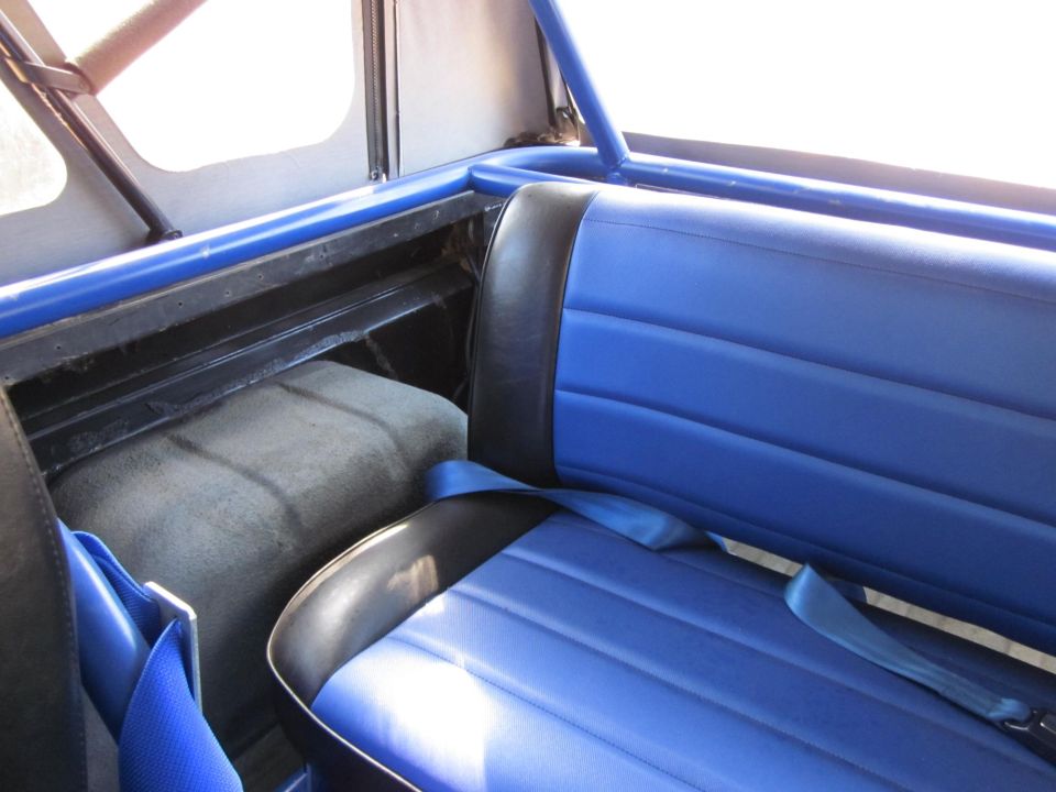 Blue and black seats with blue seatbelts inside a vehicle with a roll cage